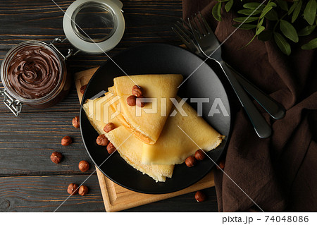 Concept of breakfast with crepes with chocolate paste and nuts on wooden table Concept of breakfast with crepes with chocolate paste and nuts on wooden table 74048086