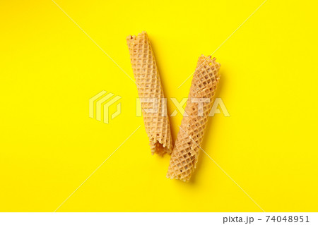 Tasty wafer rolls with condensed milk on yellow background Tasty wafer rolls with condensed milk on yellow background 74048951