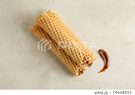 Tasty wafer rolls with condensed milk on white textured background 74048955