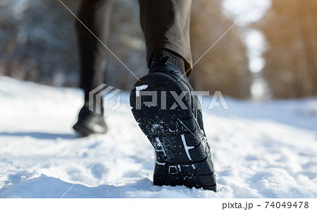 Cropped view of sportsman jogging on snowy road in winter, closeup of feet in sneakers, copy space. Outdoor activities Cropped view of sportsman jogging on snowy road in winter, closeup of feet in sneakers, copy space. Outdoor activities 74049478
