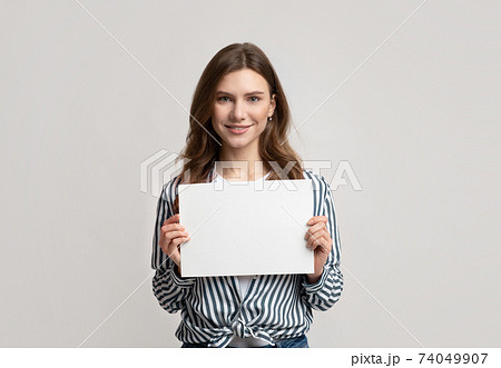Portrait of beautiful woman holding white blank advertising board Portrait of beautiful woman holding white blank advertising board 74049907