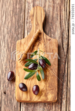 Kalamata olives with leaves on old wooden board Kalamata olives with leaves on old wooden board 74050091