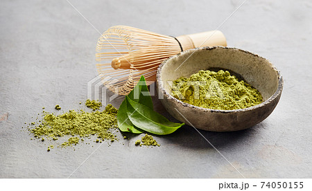 Green matcha powder with chasen bamboo whisk and tea leaves on gray background Green matcha powder with chasen bamboo whisk and tea leaves on gray background 74050155