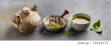 Green matcha powder with leaves and clay tea pot on graphite background 74050175