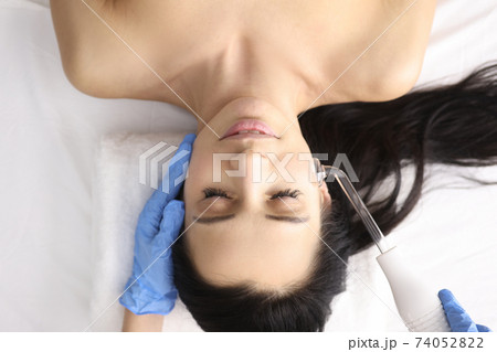 Doctor in gloves doing facial massage with darsonval Doctor in gloves doing facial massage with darsonval 74052822