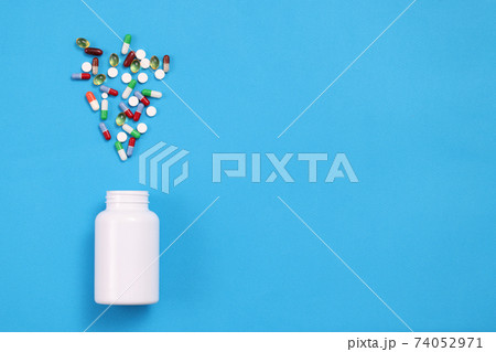 Many multicolored capsules are expelled from jar closeup 74052971