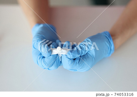 Doctors hands in rubber gloves opening rectal suppository closeup Doctors hands in rubber gloves opening rectal suppository closeup 74053316