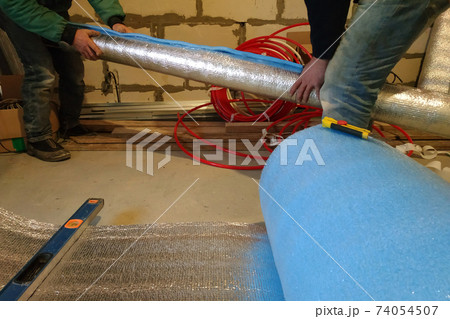 the installer and auxiliary worker wraps the air duct with mineral wool and foil 74054507