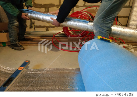 the installer and auxiliary worker wraps the air duct with mineral wool and foil 74054508