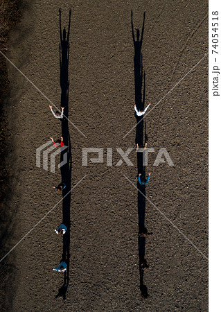 A group of children stand on the road, resulting in shadows, top view. A group of children stand on the road, resulting in shadows, top view. 74054518