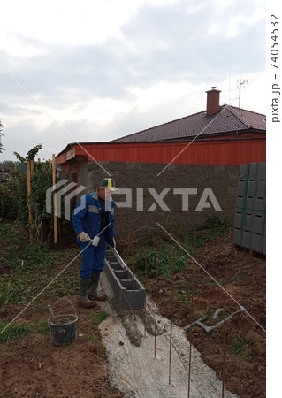 Construction of a fence on a private territory, a worker while performing work. Construction of a fence on a private territory, a worker while performing work. 74054532