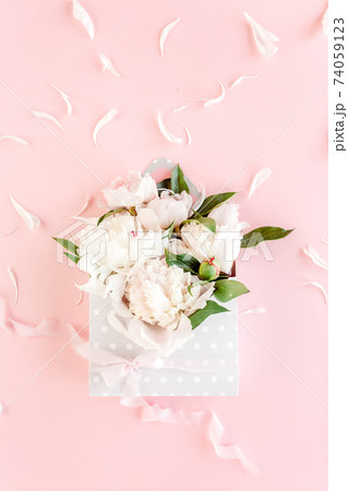 Beige bouquet of peonies in an envelope for flowers on pink background. Minimal floral concept greeting card. Flat lay, top view.  74059123