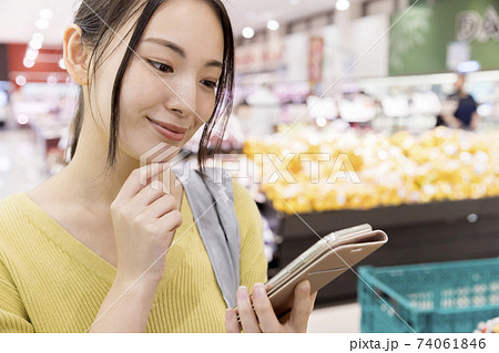 スーパーでスマホをチェックする女性買い物客 74061846