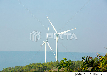 Wind power station. Wind generators stand in agricultural fields on mountain. Wonderful landscape shot from a great height. Modern green energy. Wind power station. Wind generators stand in agricultural fields on mountain. Wonderful landscape shot from a great height. Modern green energy. 74062978