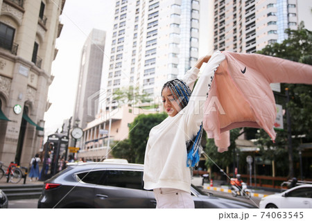 Happy stylish young hipster woman with long blue hair pink jacket, hat on the street in urban city. 74063545
