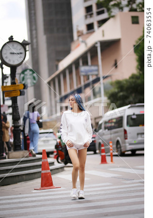Happy stylish young hipster woman with long blue hair pink jacket, hat on the street in urban city. 74063554