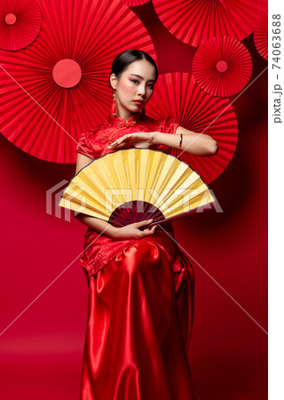 Beautiful glamourous Asian woman in traditional Chinese dress holding golden fan 74063688