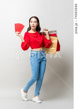 Smiling Asian woman holding shopping bags and red envelopes or Ang Pao 74063689