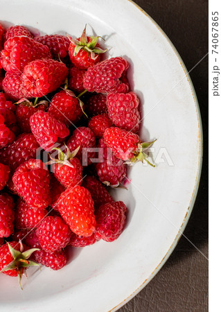 Delicious ripe raspberries from garden lie in white plate. 74067865