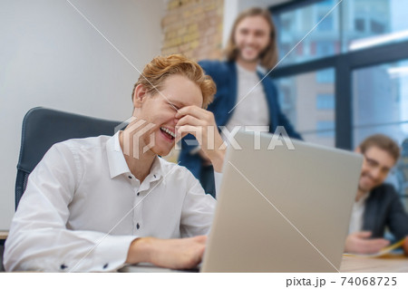 Redhaired man at laptop touching face with hand Redhaired man at laptop touching face with hand 74068725