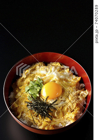 卵黄、みつば、刻み海苔の乗っている玉子丼を黒背景で撮影（俯瞰） 74070289