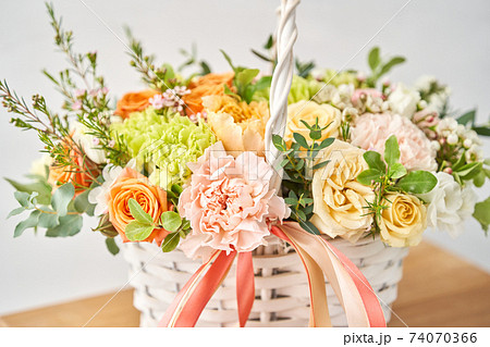 Small flower shop and Flowers delivery. Flower arrangement in Wicker basket. Beautiful bouquet of mixed flowers on wooden table. Handsome fresh bouquet. Small flower shop and Flowers delivery. Flower arrangement in Wicker basket. Beautiful bouquet of mixed flowers on wooden table. Handsome fresh bouquet. 74070366