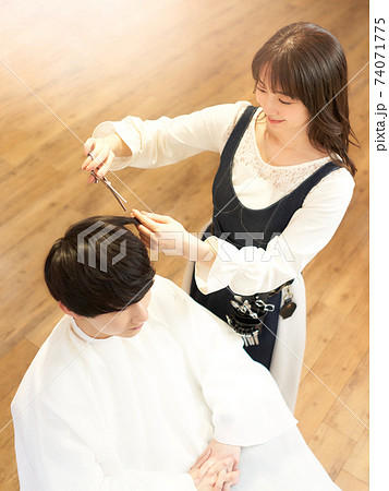 客の髪を切るヘアスタイリスト 74071775