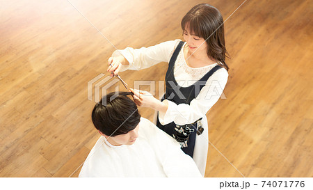 客の髪を切るヘアスタイリスト 74071776