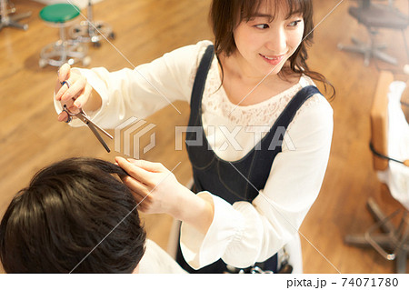 客と会話しながら髪を切るヘアスタイリスト 74071780