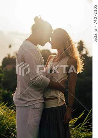 long haired man hugs his delicate curly woman in the lights of sunset long haired man hugs his delicate curly woman in the lights of sunset 74072105