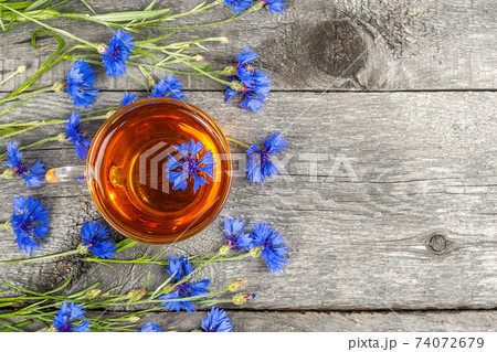 Cup of herbal tea and blue cornflowers flowers on wood background. Top view Flat lay Copy space. Cup of herbal tea and blue cornflowers flowers on wood background. Top view Flat lay Copy space. 74072679