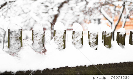 Wooden fence gate covered in white snow at heavy snowing snowstorm 74073586