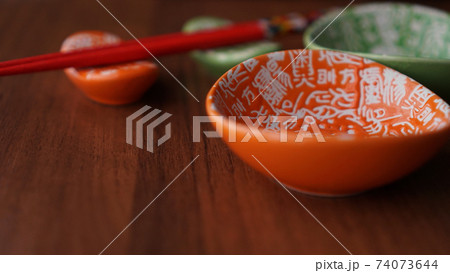 Set of ceramic dishes and red sushi sticks on wooden background Set of ceramic dishes and red sushi sticks on wooden background 74073644