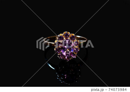 Beautiful golden ring with purple gemstone isolated on black background 74073984