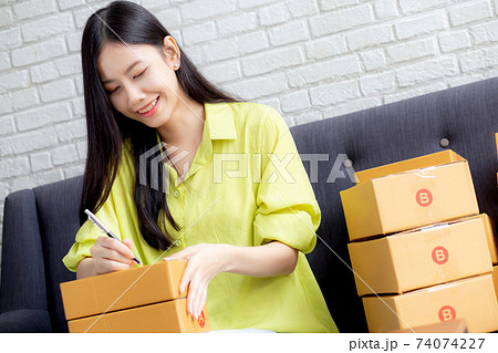 Young asian woman writing address on parcel box at home for delivery order to customer. 74074227