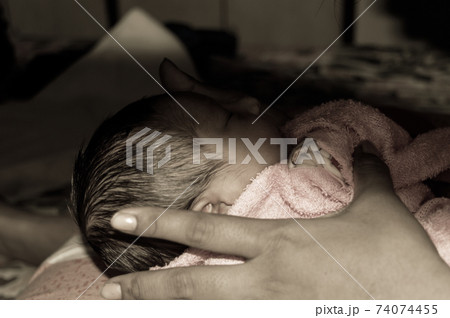 Beautiful Newborn baby boy Close up (6 days old) lying in mother lap in prenatal hospital. Kid wrapped in baby blanket (warm clothing) sleeping looking away. His mother consoling and resting her baby. Beautiful Newborn baby boy Close up (6 days old) lying in mother lap in prenatal hospital. Kid wrapped in baby blanket (warm clothing) sleeping looking away. His mother consoling and resting her baby. 74074455