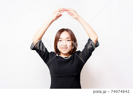 白背景の前に立って、OKのジェスチャーをする喪服を着た女性 74074642