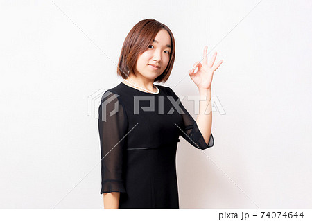 白背景の前に立って、OKのジェスチャーをする喪服を着た女性 74074644