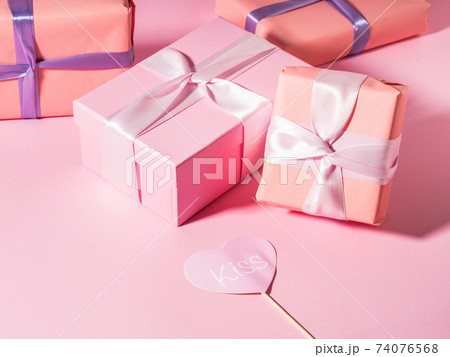 Pink wrapped gift boxes with ribbons on monochrome background Pink wrapped gift boxes with ribbons on monochrome background 74076568