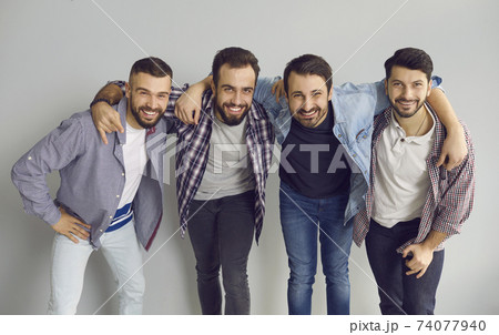 Group portrait of happy young friends hugging, smiling and having fun in the studio 74077940