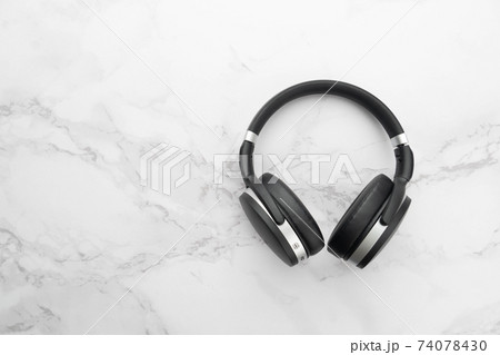 Black wireless bluetooth headphones on marble background. Music concept. Top view. Copy space. 74078430