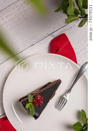 Piece of chocolate Mozart cake and fork on white plate on wooden table Piece of chocolate Mozart cake and fork on white plate on wooden table 74079531