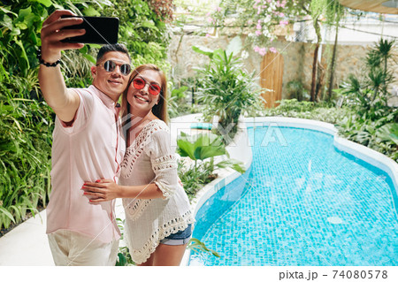 Couple hugging and taking selfie 74080578