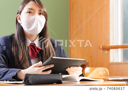 マスクをしてタブレット学習する女子高生 高校生 生徒の写真素材