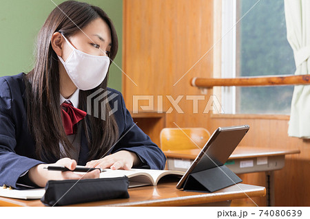 マスクをしてタブレット学習する女子高生 高校生 生徒の写真素材
