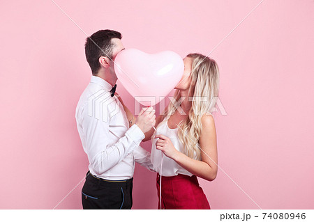 Valentines day. Beautiful romantic couple with heart balloon on pink background 74080946