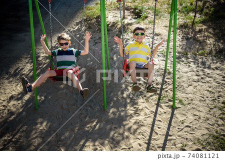 Two little kid boys having fun with swing on outdoor playground. Two little kid boys having fun with swing on outdoor playground. 74081121