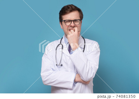 Insecure male doctor biting his nails looking funny scared craving something anxious. Insecure male doctor biting his nails looking funny scared craving something anxious. 74081350