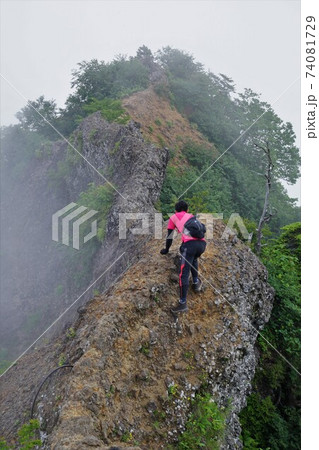 霧に包まれる戸隠山の蟻の塔渡りを歩く登山者 74081729