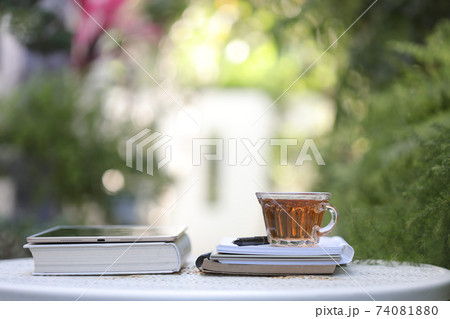 Transparent tea cup and tablet with books on white metal table at outdoor Transparent tea cup and tablet with books on white metal table at outdoor 74081880